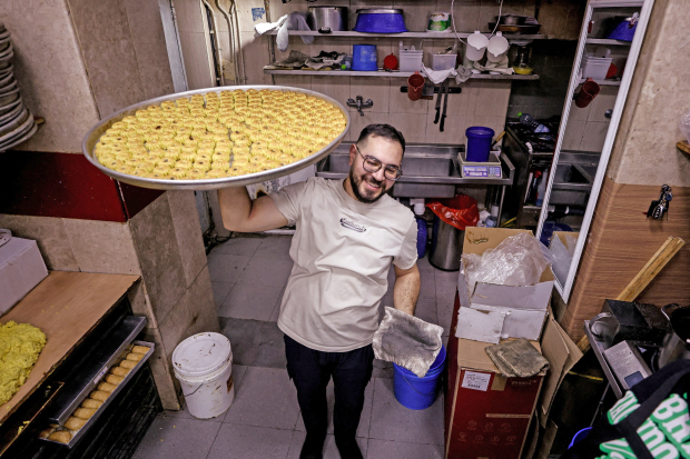 <p>A worker carries traditional sweets as Palestinians prepare for Eid Al Fitr in Jerusalem&rsquo;s Old City.</p>